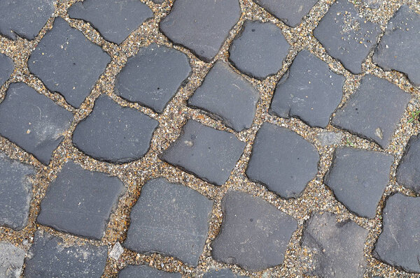 Pavement of gray granite sett stones with fine gravel in interspace in street in old town