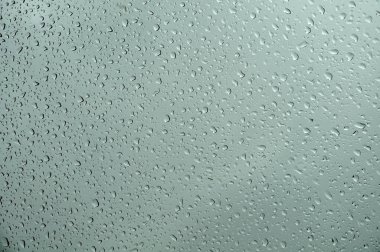 gri yağmurlu günde cam bir levha üzerinde su damlaları