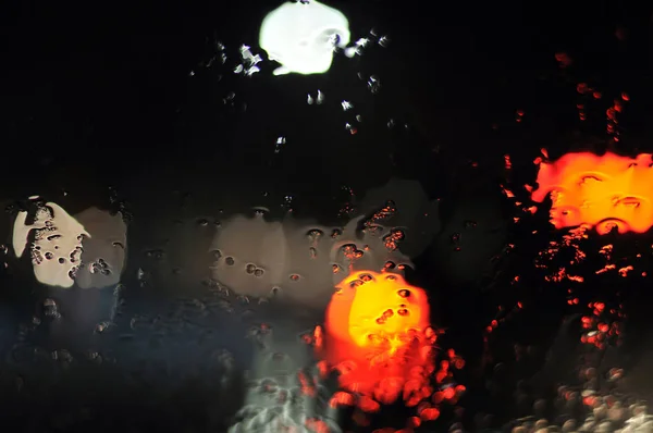 Água correndo sobre pára-brisas de um carro na noite chuvosa — Fotografia de Stock