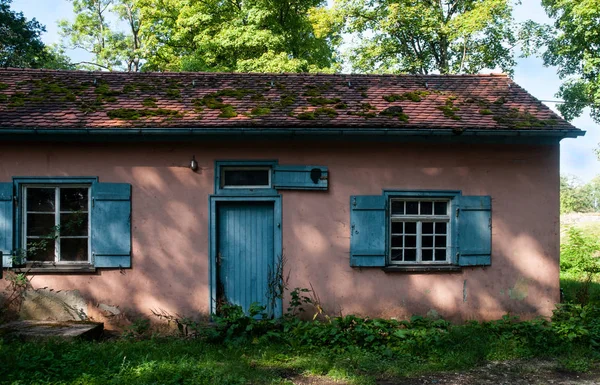 Vieille maison abandonnée avec porte bleue à l'ombre des arbres — Photo