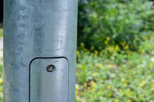 the cover of a maintenance opening at the metal post of a street light