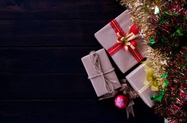 Mutlu Noel süslemeleri, hediye kutuları, altın, kırmızı, yeşil, siyah ahşap bir arka planda süslü çelenkler. Düz konumda sunar, üst görünüm, boşluğu kopyala ve görüntüyü kapat.