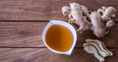 Zencefil çayı ve taze zencefil kökü dilimi. Ahşap arka planda çok kullanışlı bir bitkisel ilaç. Yakın çekim görüntüsünü sunar ve uzayı kopyalar.