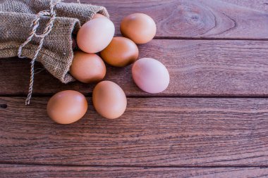 Kenevir çuvalında taze tavuk yumurtası. Ahşap bir masa üzerine kurulmuş bir çiftçi ürünü. Kopyalama alanı olan bir fotoğraf çek.