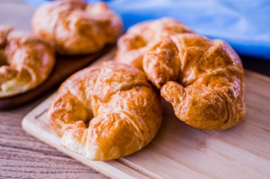 Ahşap arka planda taze kruvasan. Kahvaltı için uygun bir Fransız pastası türüdür. Dünya çapında bir pastaneden alınabilir..
