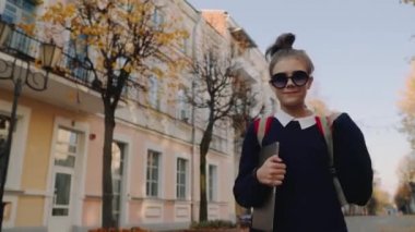 Eski Şehir caddeden aşağı yürüyüş ve gülümseyen güzel hipster genç kız. Kırmızı çanta laptop elinde tutan ile kız öğrenci. Güzel sonbahar hava.