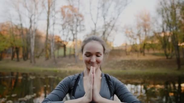 Giovane donna che pratica yoga all'aperto. Femmina meditare davanti all'aperto di bella natura autunnale . — Video Stock