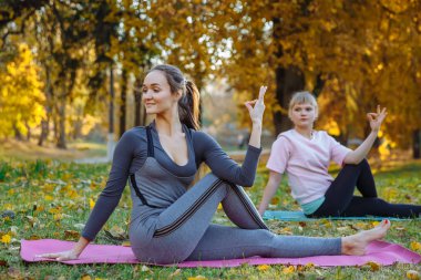 Grup Genç kadını sonbahar Şehir Parkı yoga egzersizleri yapıyor. Sağlık yaşam tarzı kavramı.