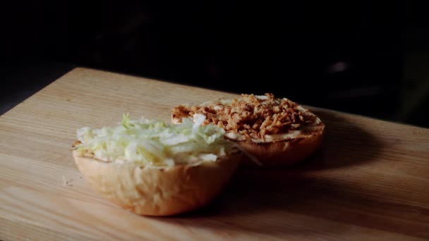 Chef haciendo hamburguesa. freír el pan en la parrilla, poner en rodajas de pepino en escabeche — Vídeos de Stock