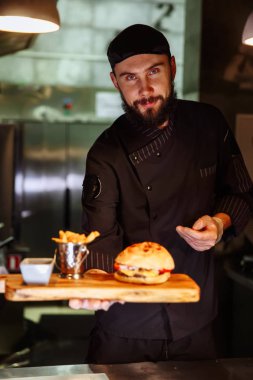 Hizmet burger ile plaka tutarak Tekdüzen bakarak kameraya, usta şef gülümseyen.