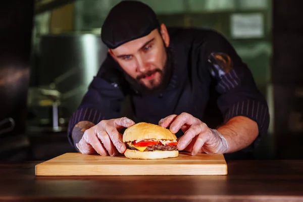 Chef putting bun on top,he making a beef burger for customer order.