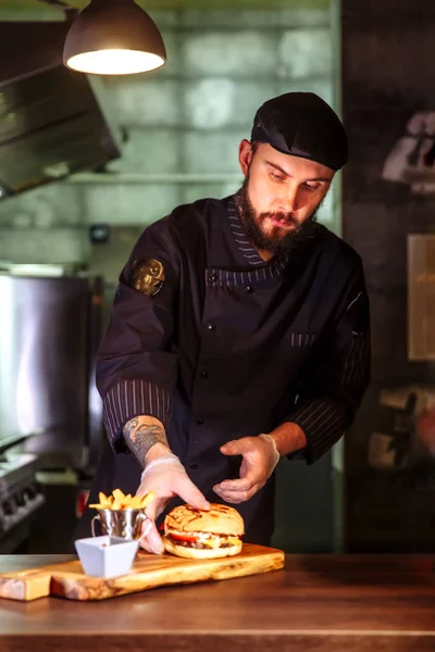 Koch legt Brötchen obendrauf, er macht einen Rindfleisch-Burger für die Kundenbestellung. — Stockfoto