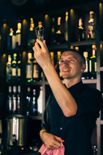 Barman guarda un bicchiere di cristallo. Il barista pulisce il bicchiere sul bancone — Foto Stock