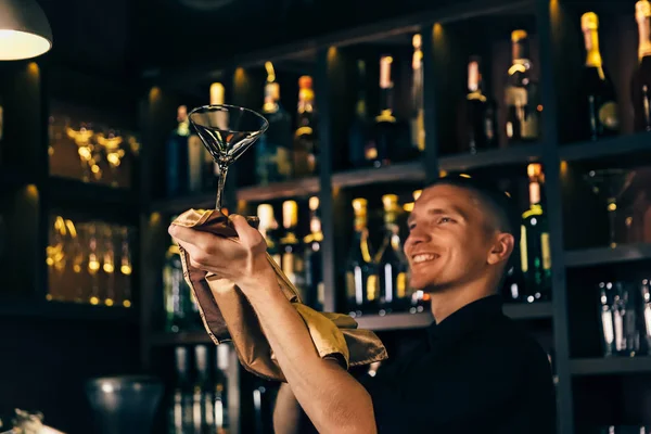 Barman mira un vaso de cristal. El camarero limpiando el vidrio en la barra — Foto de Stock