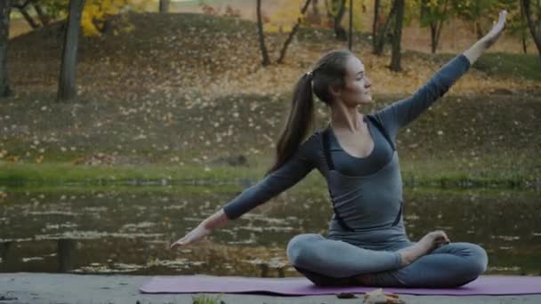 Young woman doing yoga exercises in the autumn city park. Health lifestyle concept. — Stock Video