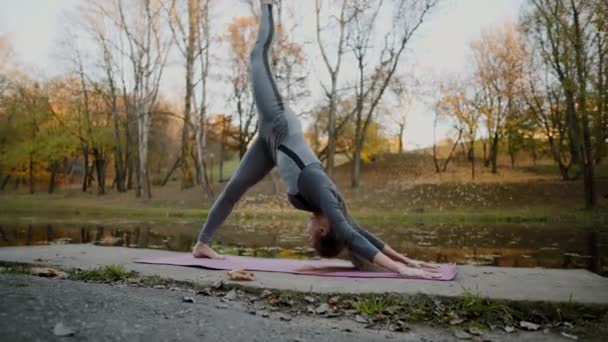 Young woman doing yoga exercises in the autumn city park. Health lifestyle concept. — Stock Video