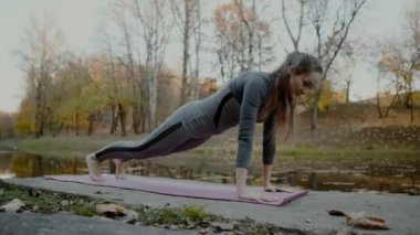 Genç kadının sonbahar Şehir Parkı Yoga egzersizleri yapması. Sağlık yaşam tarzı kavramı.