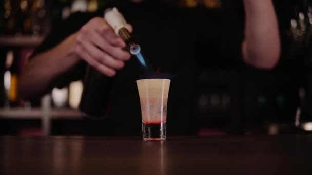 De barman maakt een cocktail van brand. Hiroshima cocktail. De barman ontbrandt de aansteker op de balk — Stockvideo