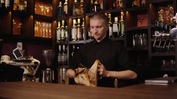 Barman está limpiando el vidrio con un paño en el fondo del mostrador de la barra. El camarero limpiando el vidrio en la barra — Vídeo de stock