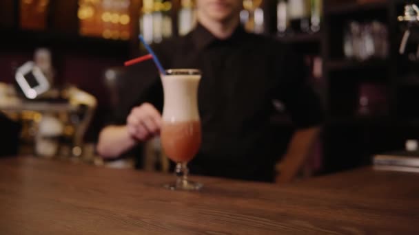 Tapster präsentiert und bringt fertigen Cocktail für die Besucher. Glas über Stehtisch vor Kamera schieben — Stockvideo