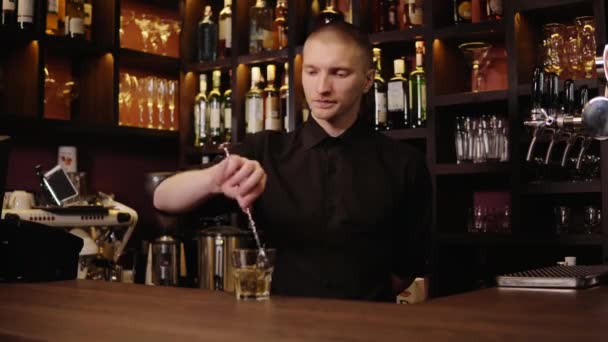 Joven barman en el interior del bar vertiendo whisky en vidrio y llevándolo para los visitantes — Vídeos de Stock