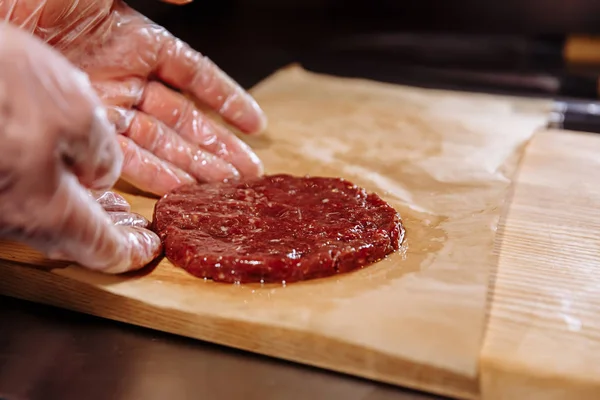 Hamburger yapma Şef. Şef gıda eldiven pirzola yapar. Beşamel sos bile bir madalyon çelik ringde seviyelendirilir. Dökme baharat biber ve tuz üstüne.