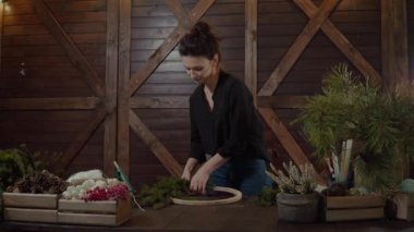 Noel çelenk ile çalışma çiçekçi kadın. Sevimli genç gülümseyen kadın Tasarımcısı Noel yaprak dökmeyen ağaç çelenk hazırlama.