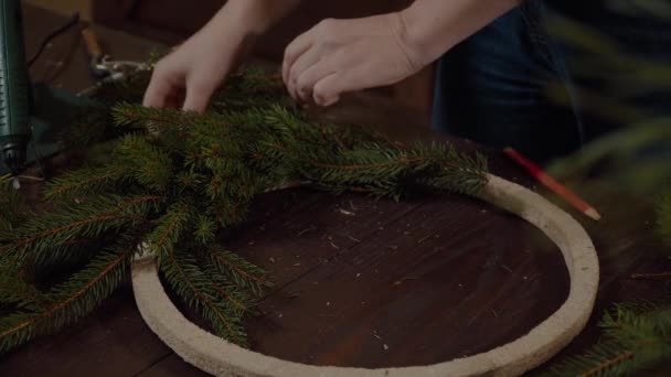 Joven linda mujer sonriente diseñador preparando la corona de árboles de hoja perenne de Navidad. Fabricante de decoración de Navidad con sus propias manos. Corona de Navidad para las vacaciones. La celebración del año nuevo. Primer plano. — Vídeos de Stock