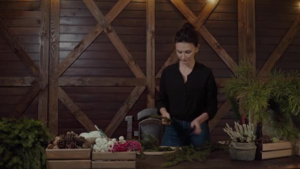 Working Florist Woman with Christmas Wreath. Young Cute smiling Woman designer preparing Christmas Evergreen Tree Wreath. — Stock Video