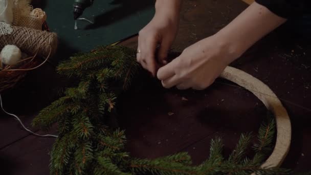 Joven linda mujer sonriente diseñador preparando la corona de árboles de hoja perenne de Navidad. Fabricante de decoración de Navidad con sus propias manos. Corona de Navidad para las vacaciones. La celebración del año nuevo. Primer plano. — Vídeos de Stock