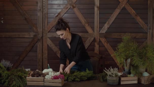 Dolgozó nő virágkötő Karácsonyi koszorú. Készül a karácsony örökzöld fa koszorú fiatal aranyos, mosolygós nő tervező. — Stock videók