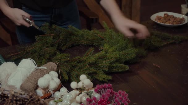 Jovem bonito sorrindo Mulher designer preparando Natal Evergreen Tree grinalda. Fabricante de decoração de Natal com suas próprias mãos. Grinalda de Natal para o feriado. A celebração do ano novo. Fechar. — Vídeo de Stock