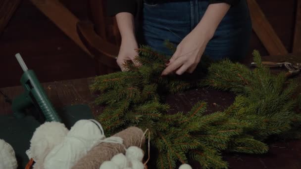 Joven linda mujer sonriente diseñador preparando la corona de árboles de hoja perenne de Navidad. Fabricante de decoración de Navidad con sus propias manos. Corona de Navidad para las vacaciones. La celebración del año nuevo. Primer plano. — Vídeo de stock