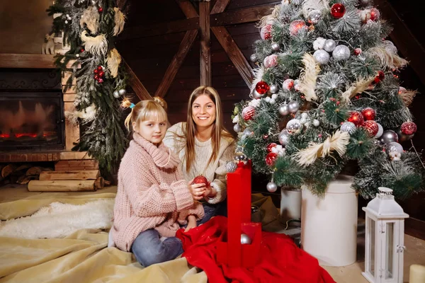 Feliz Navidad y Feliz Año Nuevo. Mamá y su hija decoran el árbol de Navidad en el interior. Familia cariñosa de cerca . — Foto de Stock