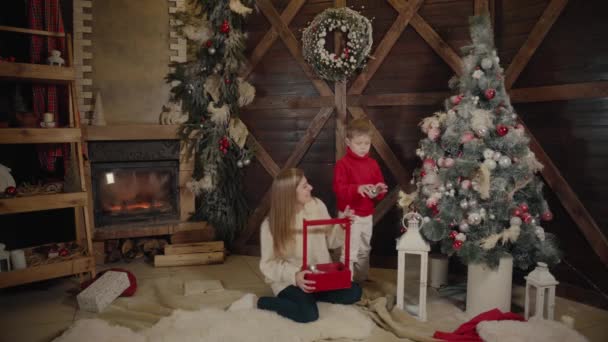 メリー クリスマスと新年あけましておめでとうございます。ママと息子は、室内にクリスマス ツリーを飾る。愛する家族をクローズ アップ. — ストック動画