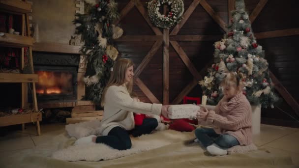 Feliz Navidad y Feliz Año Nuevo. Alegre mamá y su linda hija intercambiando regalos. Padres e hijos divirtiéndose cerca del árbol de Navidad en el interior. Familia cariñosa con regalos en la habitación . — Vídeos de Stock