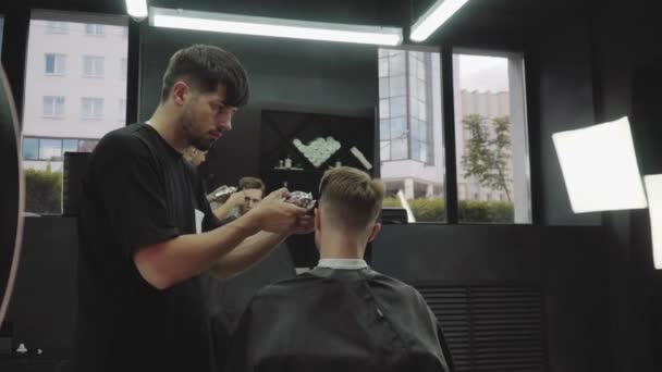 Male haircut with electric razor. Barber makes haircut for client at the barber shop by using hairclipper. Man hairdressing with electric shaver. Handheld shot. 4K. — Stock Video