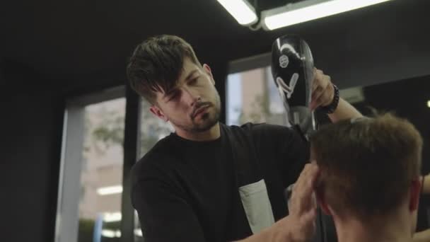 Barber drying male hair in hairdressing salon. Handheld shot. 4K. — Stock Video