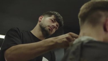 Elektrikli traşlı erkek saç kesimi. Saç kesme stilini kapat. Berber, berber dükkanında saç kesme makinesi kullanarak müşterisinin saçını kesiyor. Elektrikli traşlı erkek kuaförü. El kamerasıyla. 4K.