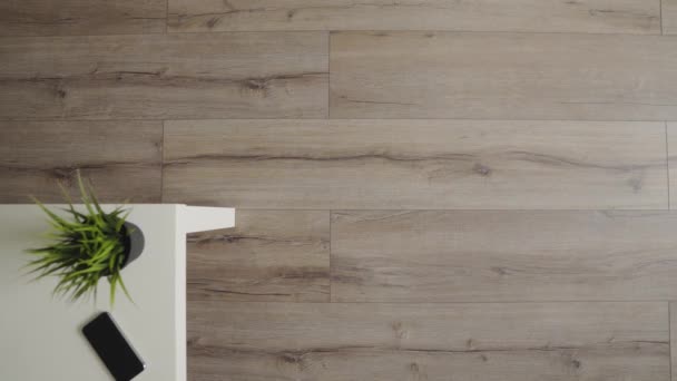 Een robot stofzuiger glijdt over de een moderne woonkamer. 4k. bovenaanzicht. — Stockvideo