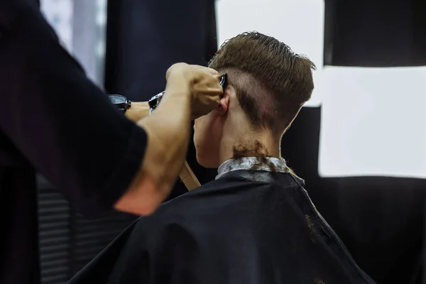 Male haircut with electric razor. Barber makes haircut for client at the barber shop by using hairclipper. Man hairdressing with electric shaver. — Stock Photo, Image