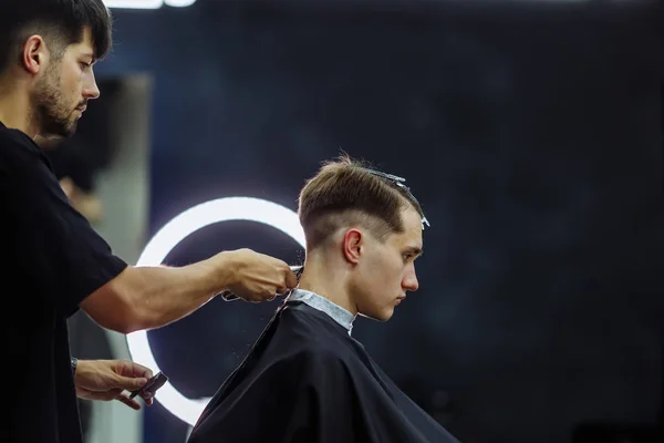 Male haircut with electric razor. Barber makes haircut for client at the barber shop by using hairclipper. Man hairdressing with electric shaver.