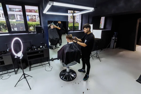 Mannelijk kapsel met elektrisch scheermes. Kapper maakt kapsel voor klant bij de kapper winkel met behulp van een tondeuse. Man kappers met elektrische scheerapparaat. — Stockfoto