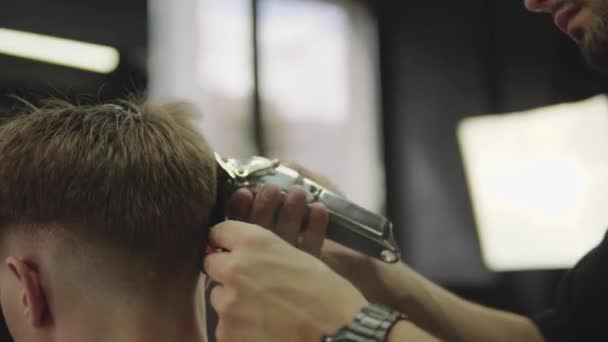 Männlicher Haarschnitt mit Rasiermesser. Nahaufnahme der Frisur des Haarschneiders. Friseur schneidet Kunden im Friseursalon mit Haarschneidemaschine. Mann frisiert mit Elektrorasierer. Handschuss. 4K. — Stockvideo