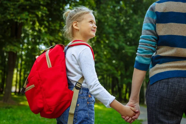 Okulda ilk gün. Arkada kırmızı sırt çantası olan kadın ve kız. Derslerin başlangıcı. Sonbaharda ilk gün. Okul konseptine geri dön.