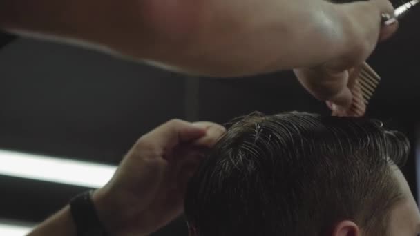 Berber, müşterinin saçını makasla keser. Kapatın. Çekici erkek berber dükkanında modern bir saç kesimi yaptırıyor. El kamerasıyla. 4K. — Stok video