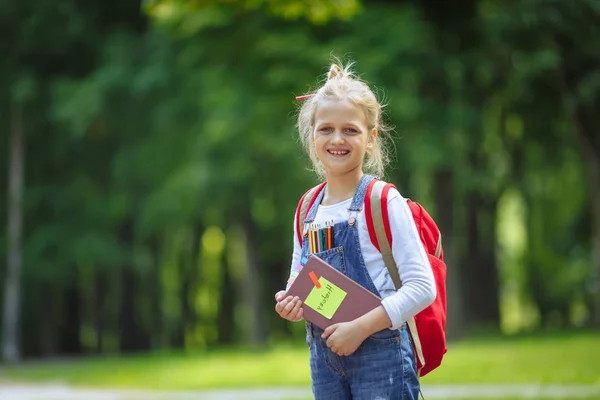 Portrait d'écolière heureuse avec livre et sac à dos rouge. Concept de retour à l'école . — Photo