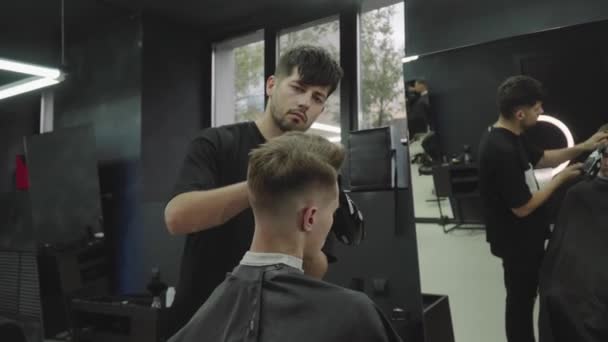 Corte de pelo masculino con afeitadora eléctrica. Peluquero hace corte de pelo para el cliente en la peluquería mediante el uso de peluquero. Peluquería hombre con afeitadora eléctrica. Un disparo de mano. 4K . — Vídeo de stock