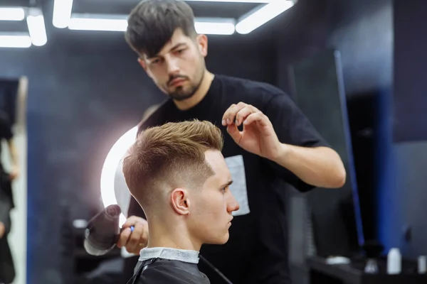 Berber kuaförde erkek saçını kurutuyor.