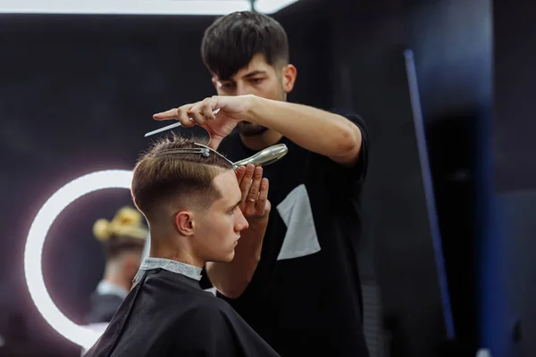 Elektrikli traşlı erkek saç kesimi. Berber, berber dükkanında saç kesme makinesi kullanarak müşterisinin saçını kesiyor. Elektrikli traşlı erkek kuaförü..